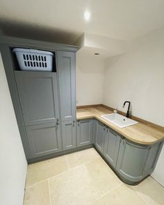 an empty kitchen with grey cabinets and white counter tops is seen in this image from the corner