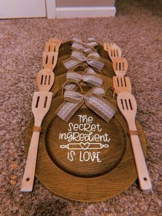 a wooden plate with utensils on it that says the secret ingredient is love