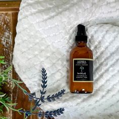 a bottle of liquid sitting on top of a white blanket next to a green plant