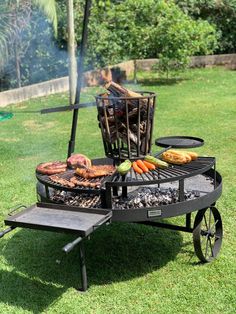 an outdoor bbq grill with meat and vegetables cooking on it's side in the grass