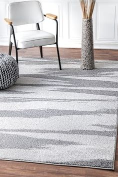 a white chair sitting on top of a wooden floor next to a gray and white rug