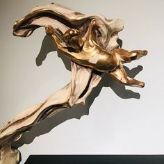 a gold sculpture is on display against a white wall