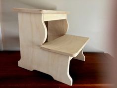 a small wooden step stool sitting on top of a hard wood floor next to a wall