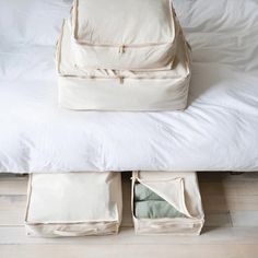 an open suitcase sitting on top of a bed next to two folded blankets and pillows