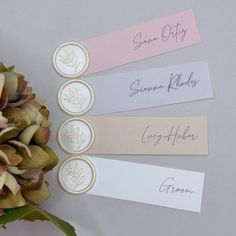 three name tags are placed on top of a bouquet of flowers and some other items