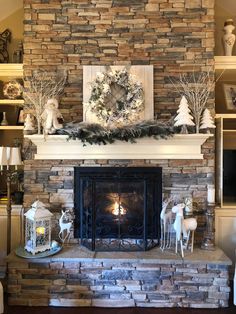 a fireplace decorated for christmas with white deer and wreaths on it's mantle