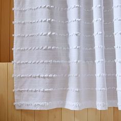 a white curtain hanging on the side of a wooden wall