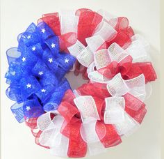 an american flag wreath hanging on the wall with red, white and blue mesh ribbons