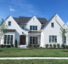 a large white house with lots of windows on the front and side of it's roof