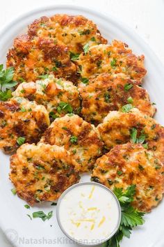 crab cakes on a white plate with a small bowl of ranch dressing next to it