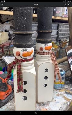 two snowmen are standing next to each other in front of some paintbrushes