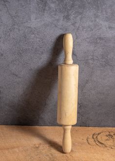 a wooden mannequin standing on top of a wood table next to a gray wall