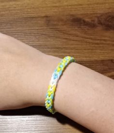 a person's arm with a yellow and blue braided bracelet on top of it