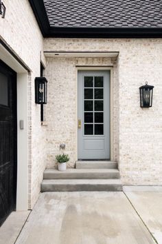 the front door of a house with two lights on each side and a potted plant next to it