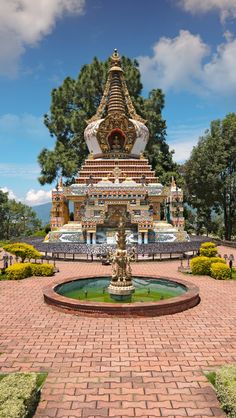 an ornate fountain in the middle of a brick walkway surrounded by greenery and trees