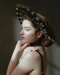 a woman with spiked hair wearing a black dress and holding her hand on her shoulder