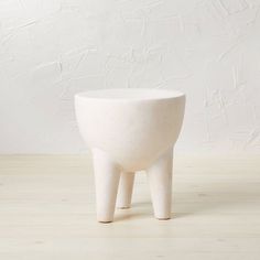 a small white planter sitting on top of a wooden floor next to a wall