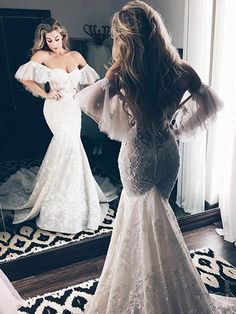 a woman in a wedding dress looking at herself in the mirror while she is getting ready for her big day