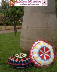 two decorative pillows sitting in the grass next to a tree