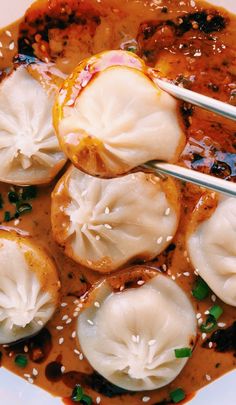 dumplings in sauce with chopsticks sitting on top of the dish, ready to be eaten