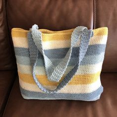 a crocheted tote bag sitting on top of a brown leather couch next to a pillow