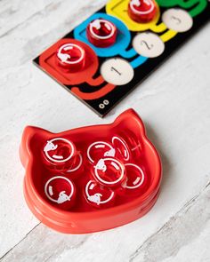 a red cat shaped plastic toy next to a matching game board on a white table