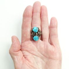 This is an Old Navajo Double Turquoise Ring Intricate Appliques Size 7.25 Sterling Silver C1970s. This size 7.25 Native American ring includes two polished turquoise stones (one with pyrite inclusions) surrounded by intricate twisted wire and appliques. The ring acid tests positive for sterling silver. The face measures 1 inch, and the ring weighs 9.1 grams. 2235635 More Native American Jewelry https://www.etsy.com/shop/redroselady?ref=hdr_shop_menu&section_id=15506102 More Southwestern Jewe Antique Turquoise Ring With Patina, Vintage Turquoise Cabochon Ring, Vintage Cabochon Turquoise Ring, Vintage Turquoise Multi-stone Rings, Vintage Multi-stone Turquoise Jewelry, Vintage Turquoise Multi-stone Jewelry, Vintage Adjustable Turquoise Ring, Vintage Oval Turquoise Ring, Adjustable Nickel Free Vintage Turquoise Ring