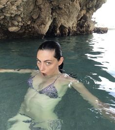 a woman is swimming in the water near rocks