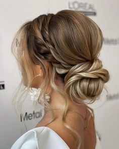 a woman with blonde hair in a low braid updo, wearing a white dress