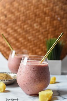 two glasses filled with smoothie sitting on top of a table