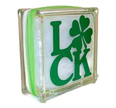 a glass block with the word luck written in green on it and a shamrock leaf