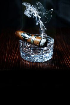 a glass ashtray with two cigars in it