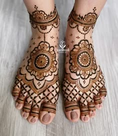 the feet and hands of a woman with henna tattoos