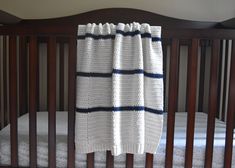 a crib with a white and blue blanket hanging from it's side