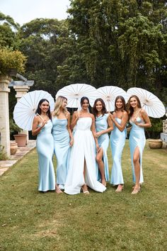 the bridesmaids are all dressed in blue dresses and holding white parasols