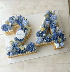 a cake shaped to look like the number twenty four with blue flowers on it and gold trimmings