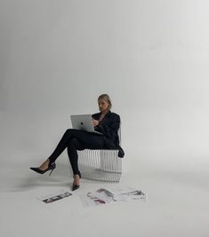 a woman sitting on a chair with her laptop in front of her and papers scattered around her