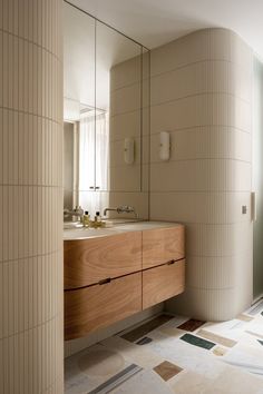 a bathroom with two sinks, mirrors and tiled flooring in beige tones on the walls