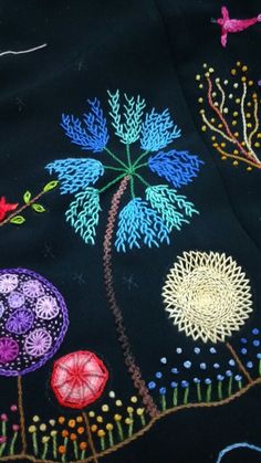 an embroidered black cloth with colorful flowers and birds in the sky on top of it