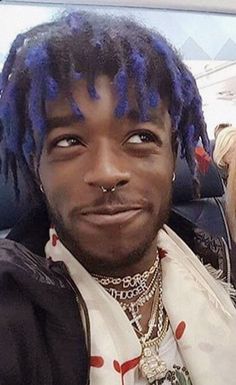 a man with blue dreadlocks is sitting in a car and looking at the camera