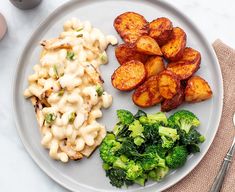 a white plate topped with macaroni and cheese next to broccoli on a table