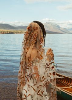 a woman standing in front of a boat on the water with her back to the camera