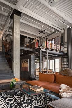 a living room filled with furniture next to a stair case in a loft style building