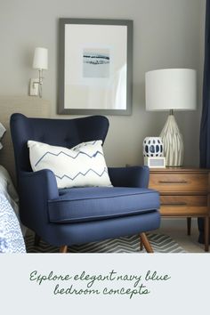 a blue chair sitting in front of a lamp next to a dresser with a painting on it