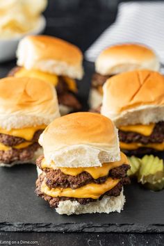 mini cheeseburgers with pickles on a black slate board, ready to be eaten