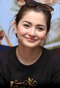 a woman wearing sunglasses and smiling at the camera with her hair in a bunt