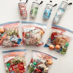 six bags filled with food sitting on top of a white table next to each other