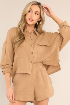 This tan top features a collared neckline, dropped shoulders, chest pockets, a full button front, button cuffed long sleeves, and a cropped hemline.