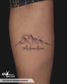 a tattoo with the words adventure written on it and mountains in the distance behind it