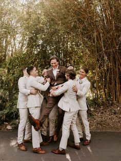 a group of men standing next to each other in front of bamboo trees and bushes